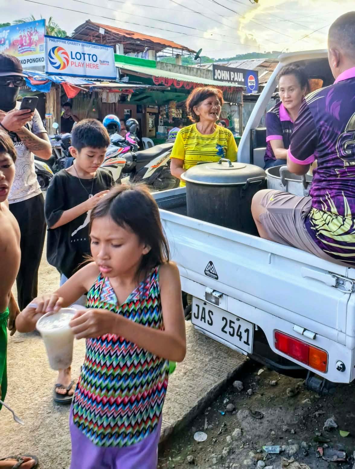 Residents receiving a community meal from volunteers beside a service vehicle